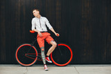 Hipster with bycicle and tatoo at dark background