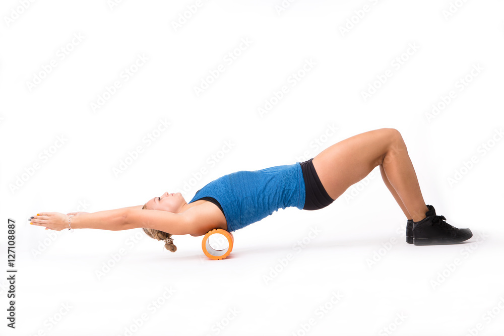 Fitness woman stretching in studio. Young athletic woman training with massage device isolated on white background in studio. Push ups concept. Fitness woman stretching in studio. Young athletic woman training with massage device isolated on white background in studio. Push ups concept.