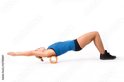 Fitness woman stretching in studio. Young athletic woman training with massage device isolated on white background in studio. Push ups concept.