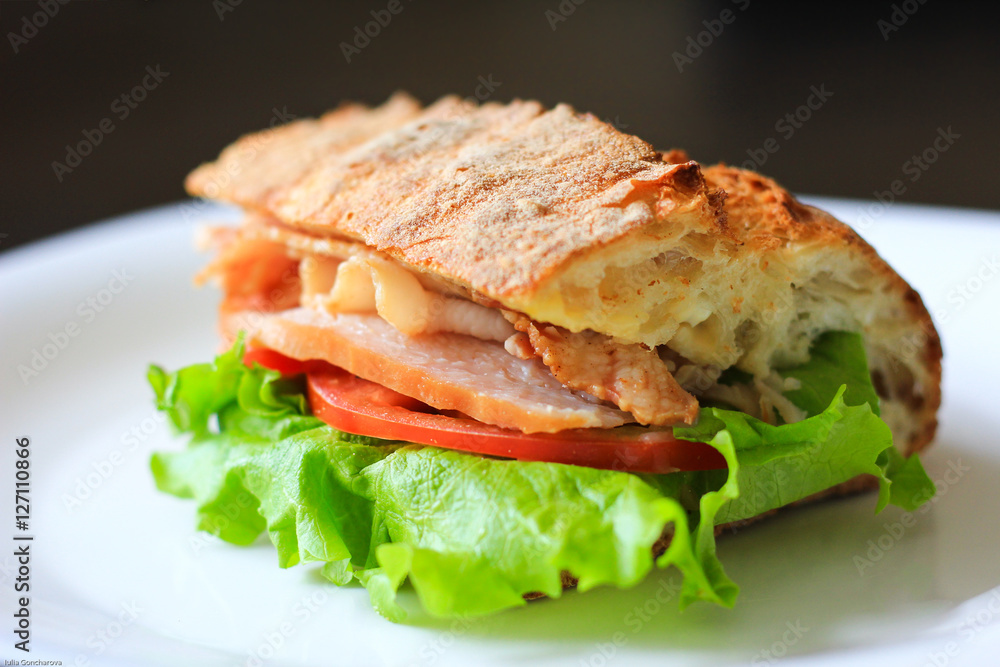Delicious sandwich with lettuce leaf, tomato and ham on a white plate. Delicious sandwich with lettuce leaf, tomato and ham on a white plate.