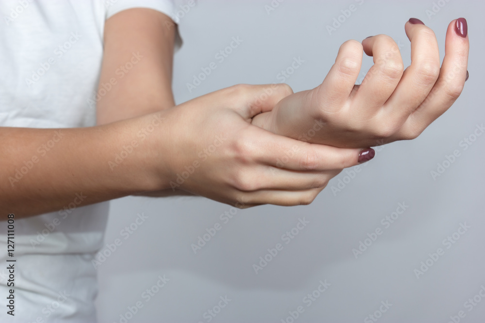 Fototapeta premium Close up woman's hand holding her wrist over gray background