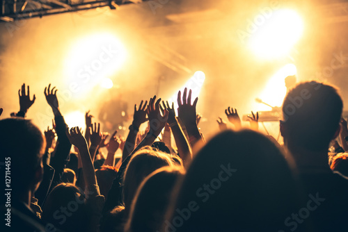 silhouettes of hands on concert in front of bright stage lights