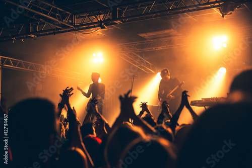 silhouettes of hands on concert in front of bright stage lights