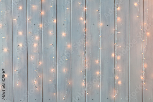 Christmas lights burning on a white wooden background. New Year back.
