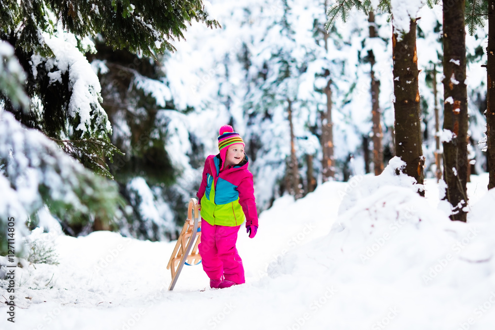 Child playing in snow on sleigh in winter park Child playing in snow on sleigh in winter park
