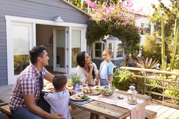 Family At Home Eating Outdoor Meal In Garden Together