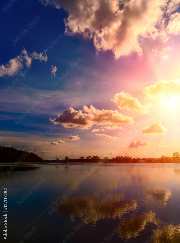 breathtaking scenery. dark-blue sky with clouds. reflection in water, for design . multicolored majestic sunset with a halo of sunlight. fantastic picturesque scene. use as background
