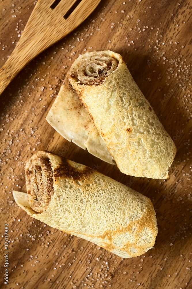 Crepe rolls filled with cinnamon and sugar, photographed overhead on wood with natural light (Selective Focus, Focus on the top of the rolls) Crepe rolls filled with cinnamon and sugar, photographed overhead on wood with natural light (Selective Focus, Focus on the top of the rolls)