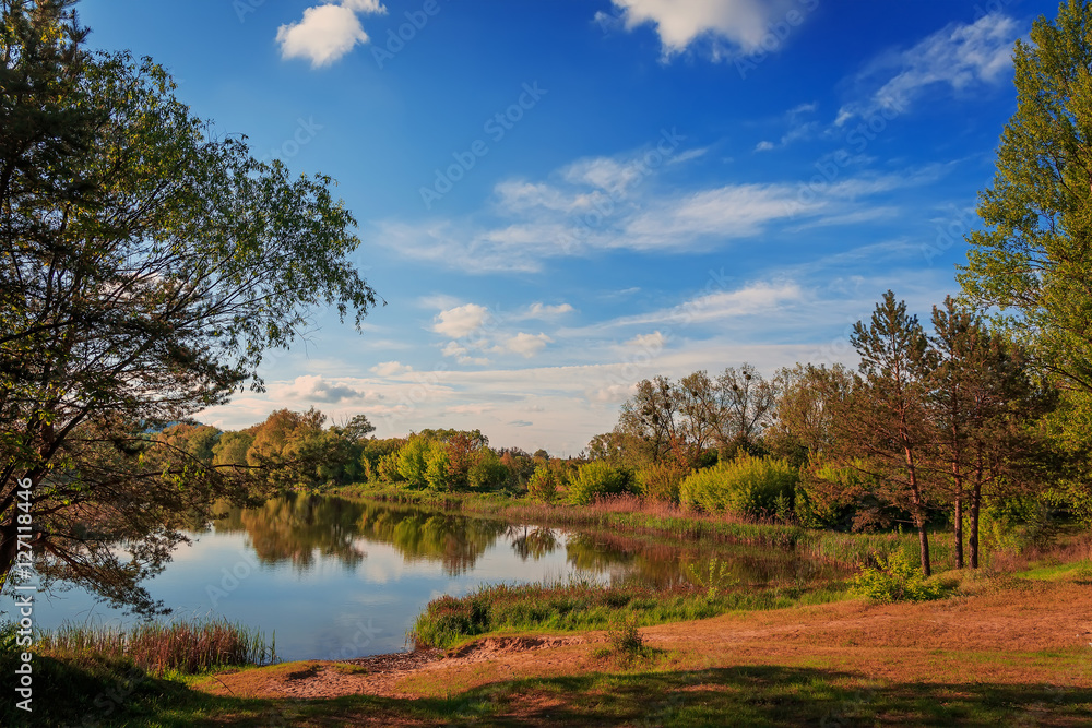 A beautiful view by the lake during sunset on a summer evening. majestic picturesque sky are reflecting from the still water. Dramatic scenic summer scene. Beauty in the world A beautiful view by the lake during sunset on a summer evening. majestic picturesque sky are reflecting from the still water. Dramatic scenic summer scene. Beauty in the world