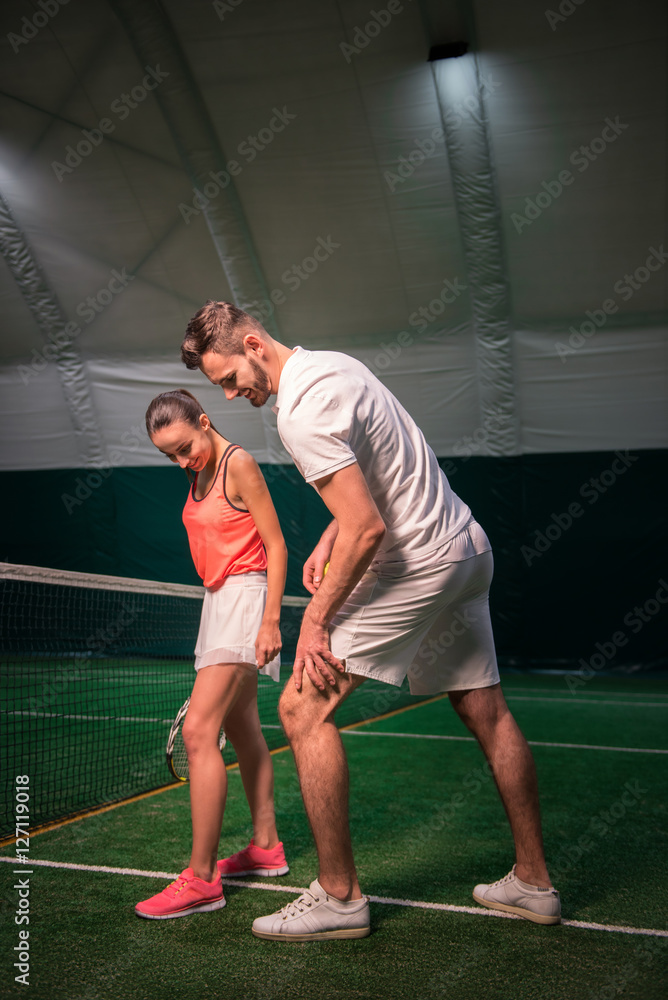 Positive tennis instructor teaching young woman