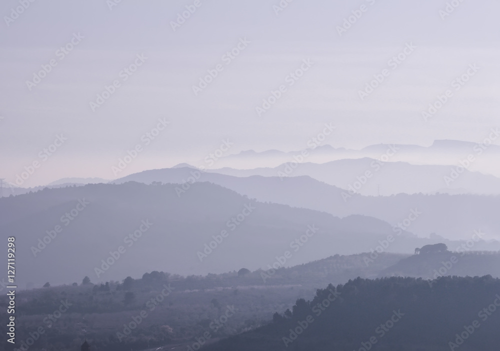 Mountains covered with heavy purple fog at sunset.