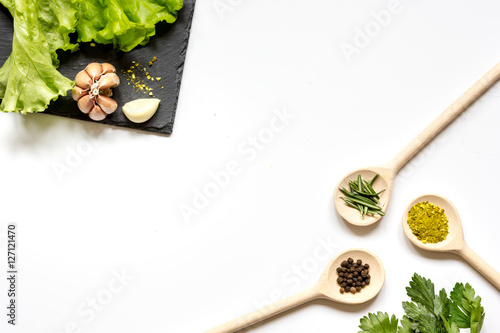 various spices in wooden spoons on white background top view