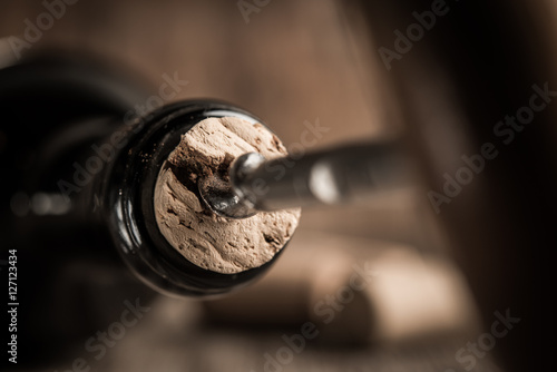 Corkscrew screwed into the cork in bottle of wine