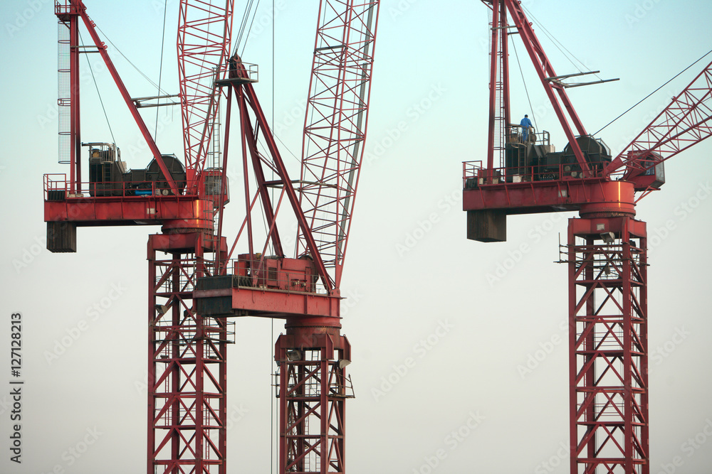 Red construction Cranes against blue sky