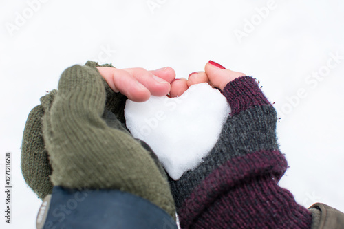 Couples hands holding heart shaped snowball