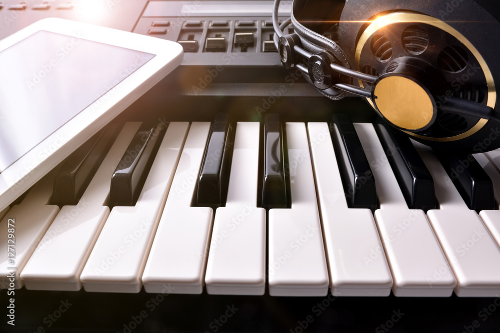 Obraz premium Electronic piano with headphones and tablet in studio front