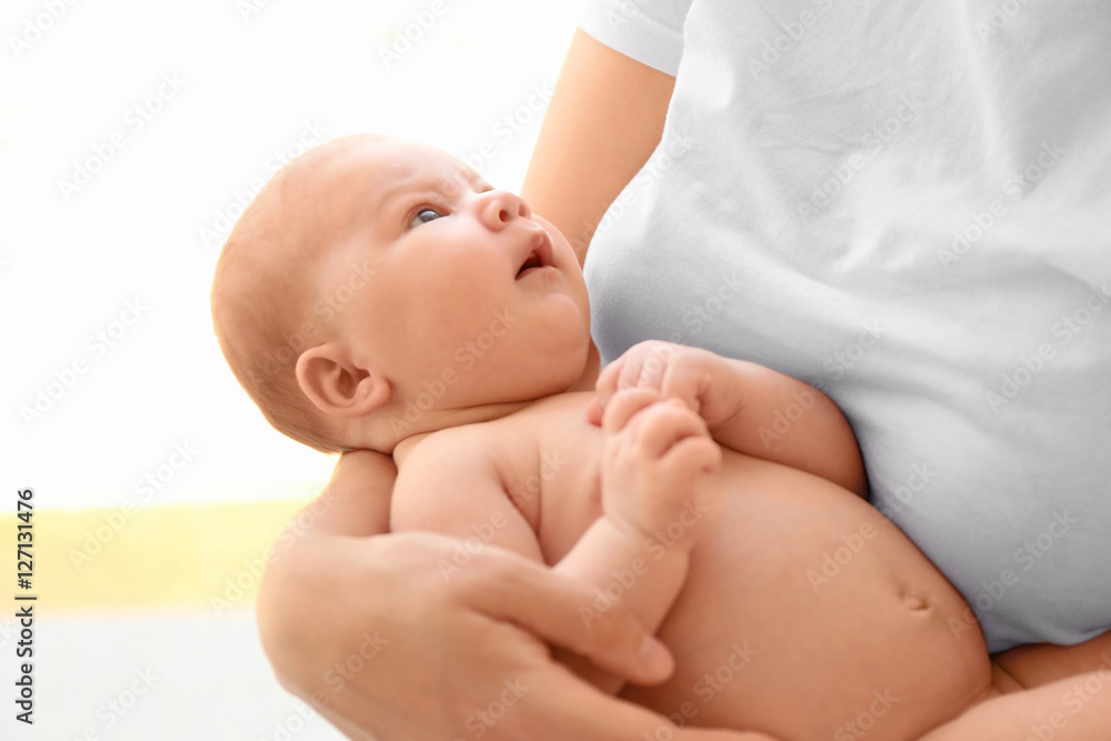 Woman holding cute baby girl on light background Woman holding cute baby girl on light background