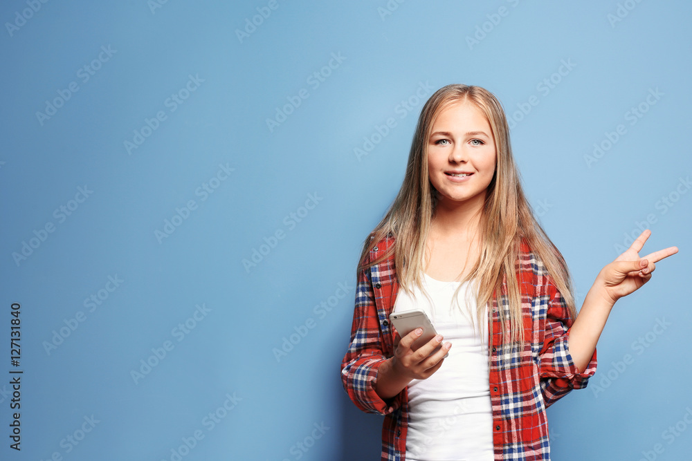 Beautiful teenager girl using smart phone on blue background Beautiful teenager girl using smart phone on blue background