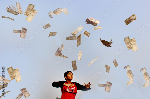 A child is trying to catch money what is no longer in use. It is now just an object of playing. 