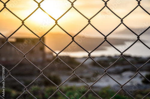 A close-up picture of fence with a blur evening scene