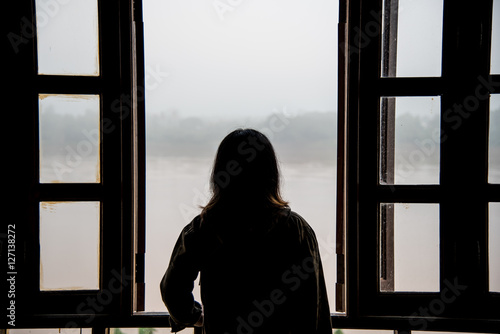 Silhouette of a young woman open window