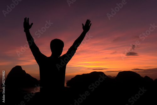  silhouette of man standing and open arms raised towards sky con