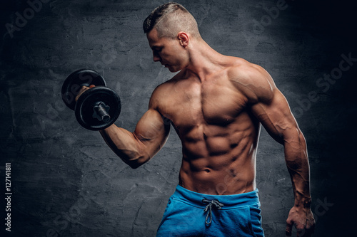 Athletic young male holds dumbbell.