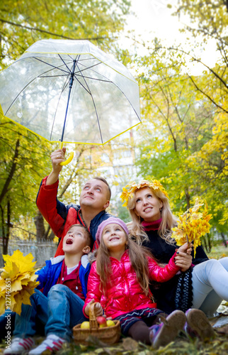 Amazed family of four under umbrella