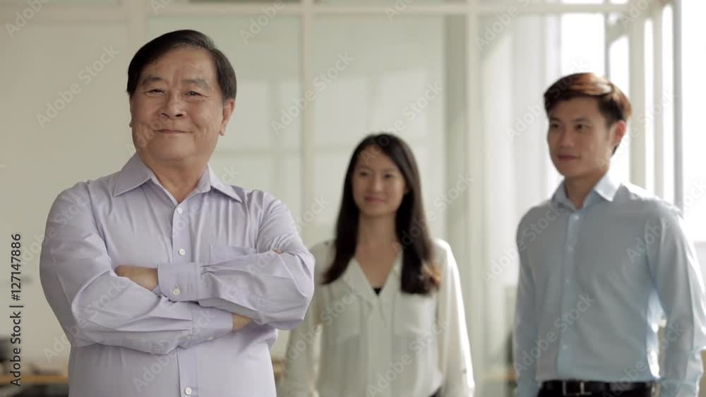 MS Senior Businessman turning from his colleagues to face camera / Singapore MS Senior Businessman turning from his colleagues to face camera / Singapore