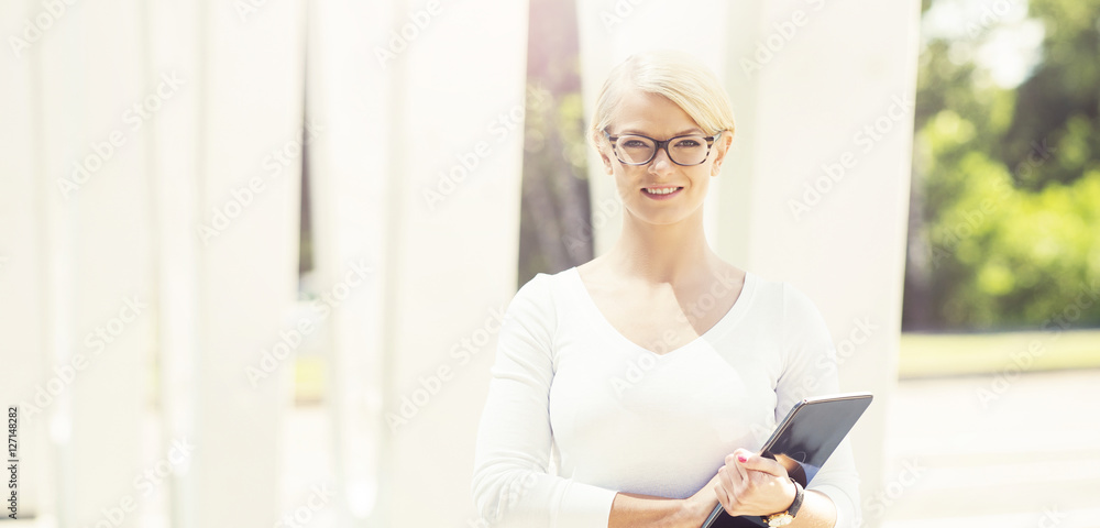Young blond businesswoman with a tablet outdoors