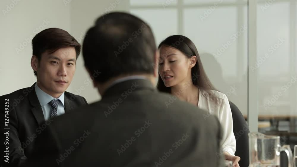 MS SELECTIVE FOCUS PAN Three colleagues in discussion at meeting table / Singapore MS SELECTIVE FOCUS PAN Three colleagues in discussion at meeting table / Singapore