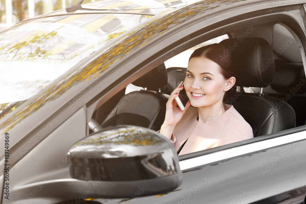 Naklejka premium Beautiful woman with cellphone driving a car