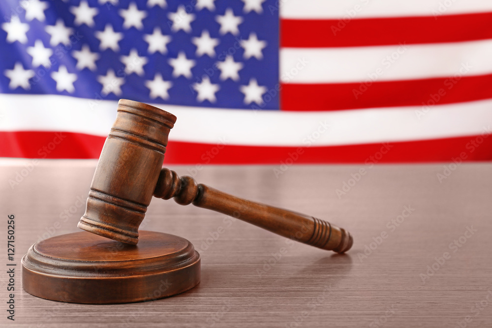 Wooden gavel on table against blurred USA flag