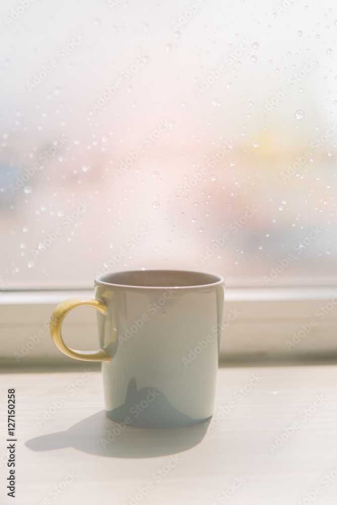 Fototapeta premium Coffee cup on table with rain drop on window background,retro e