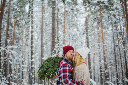 young couple with fir twigs walk in the winter woods