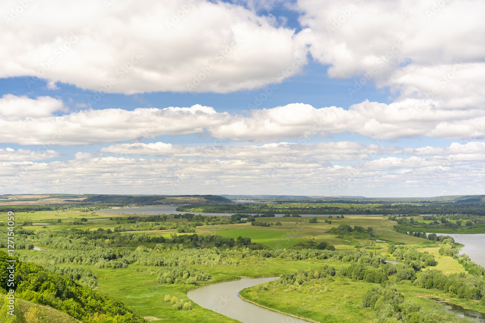 Fototapeta premium Blue sky with clouds over a green river valley