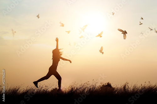 Woman and flying birds enjoying life in nature on sunset background
