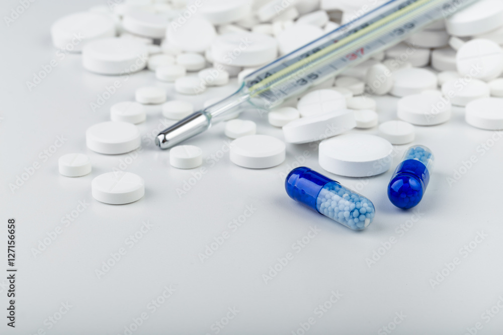 Bunch of white tablets with blue pills and thermometer. Bunch of white tablets with blue pills and thermometer.