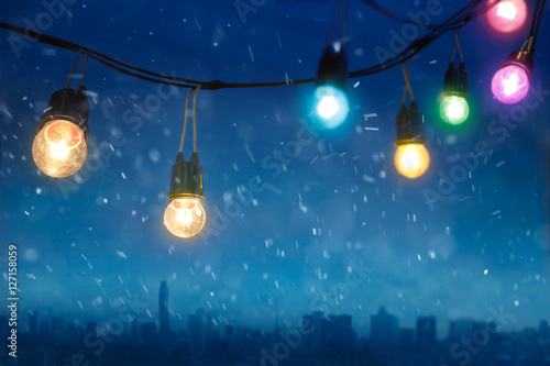 Fototapeta Naklejka Na Ścianę i Meble -  Colourful glowing christmas lights in snowfall on the dark blue