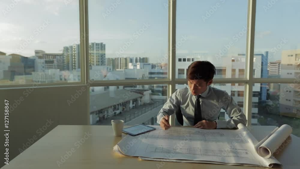 MS SELECTIVE FOCUS Young architect looks over building plans on his desk / Singapore MS SELECTIVE FOCUS Young architect looks over building plans on his desk / Singapore