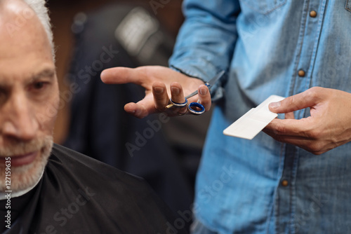 Close up of male barber holding scissors and comb