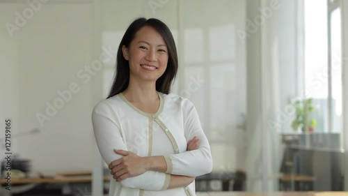 MS SELECTIVE FOCUS Businesswoman turns to look at camera, folds her arms and smiles / Singapore