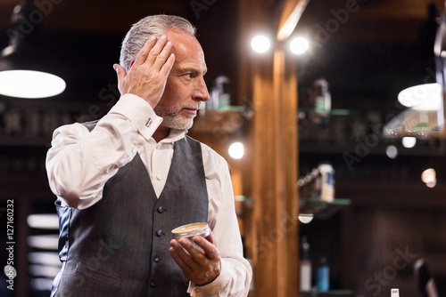 Senior businessman with hair gel in front of mirror photo