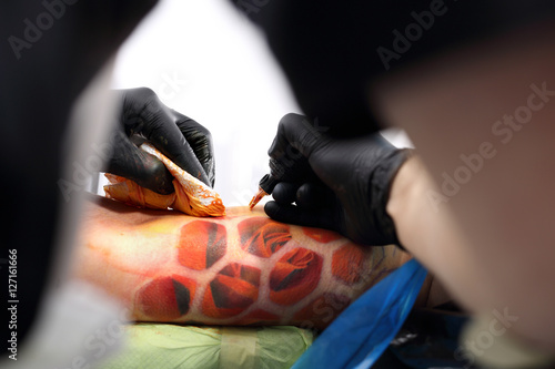 Wykonywanie tatua  u. Tatuowanie rysunku na ramieniu.