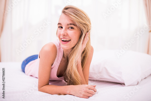 Beautiful young blonde girl in her bed with smile