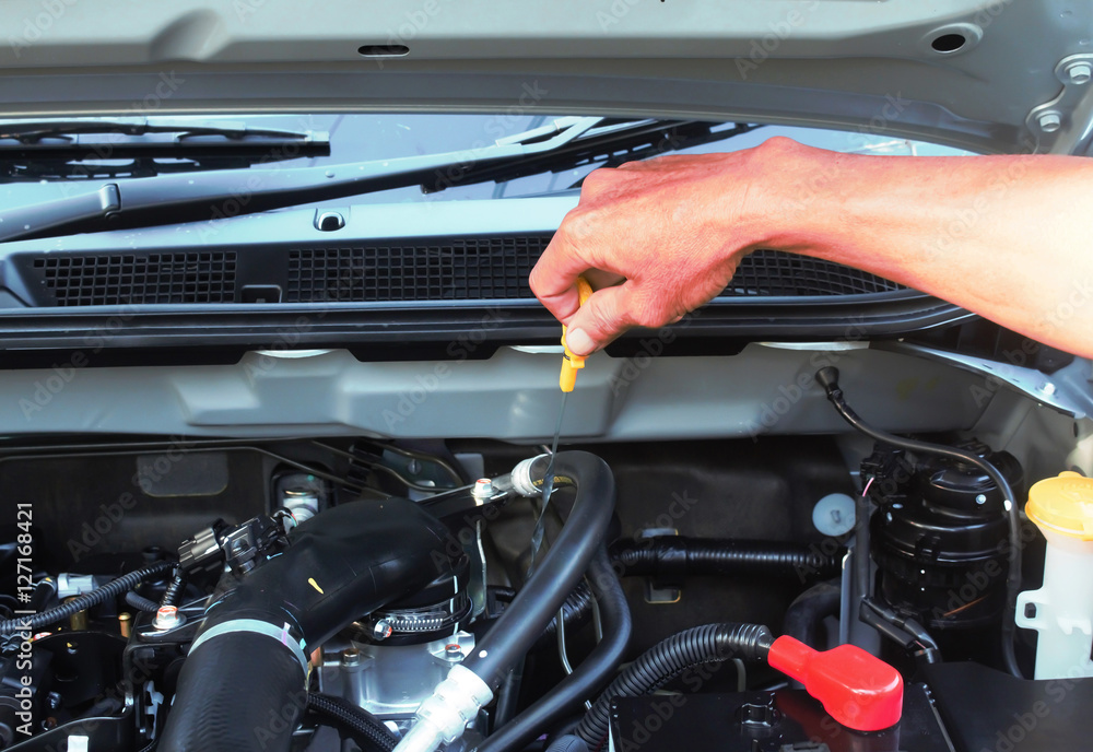 Man checking oil in his car using dipstick Man checking oil in his car using dipstick