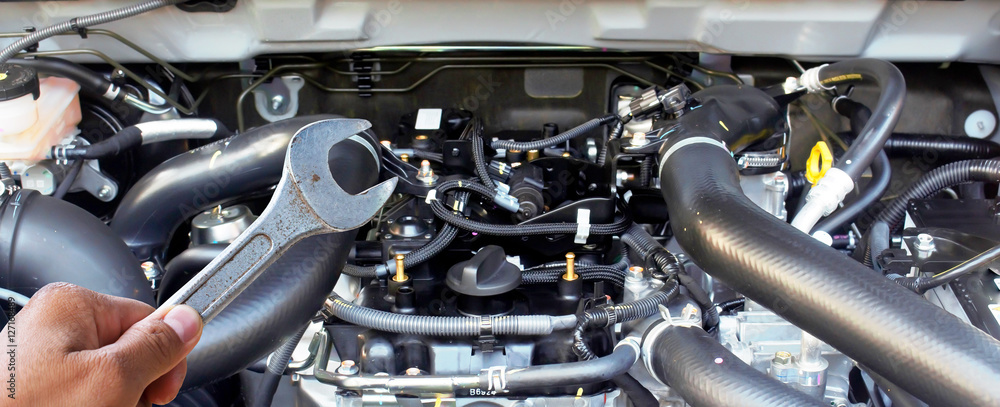 Obraz premium Hand with wrench checking car engine