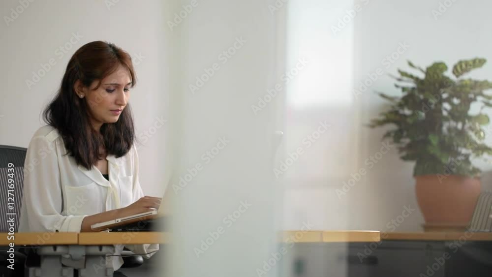 MS SELECTIVE FOCUS PAN Woman typing on laptop behind glass wall / Singapore MS SELECTIVE FOCUS PAN Woman typing on laptop behind glass wall / Singapore
