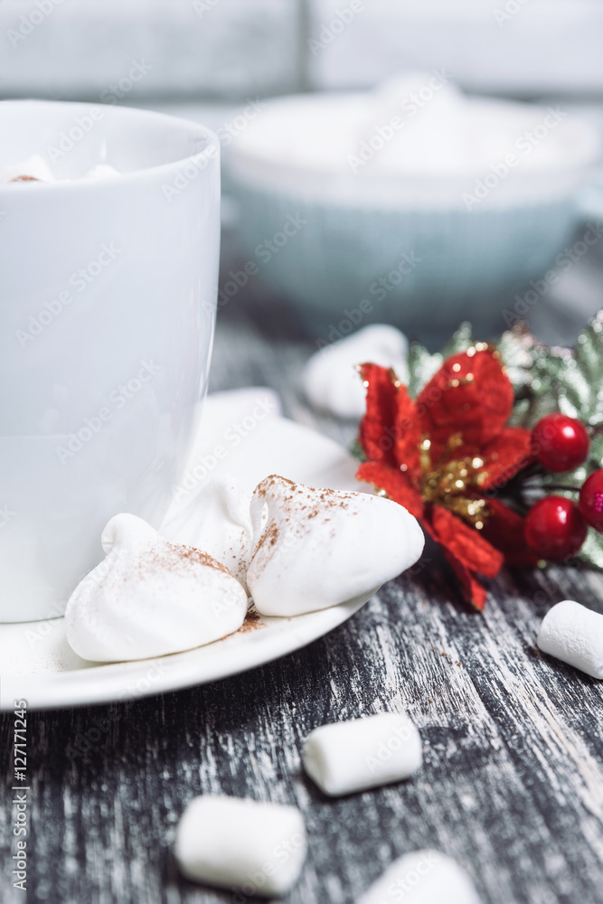 Hot chocolate with marshmallows. Drink in a white ceramic cup with zephyr on wooden table. Red poinsettia flower on plate, saucer. Hot chocolate with marshmallows. Drink in a white ceramic cup with zephyr on wooden table. Red poinsettia flower on plate, saucer.