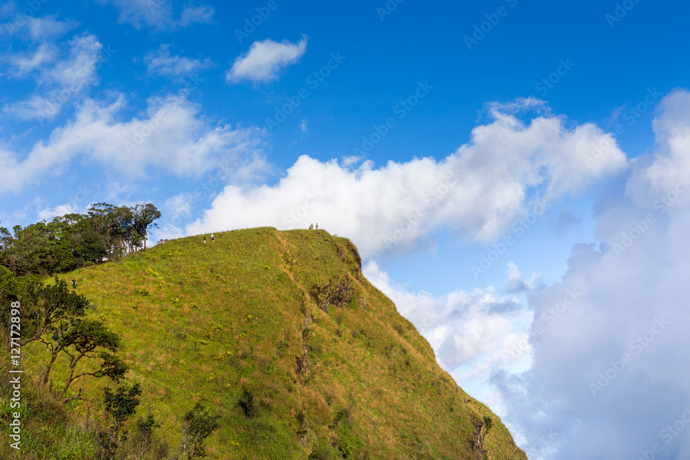 people hiking to top of mountain with blue sky